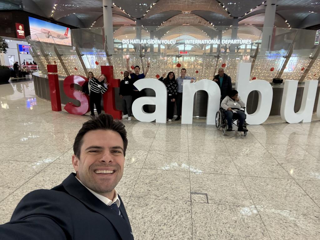 Students pose in front of the word "Istanbul" at the airport.