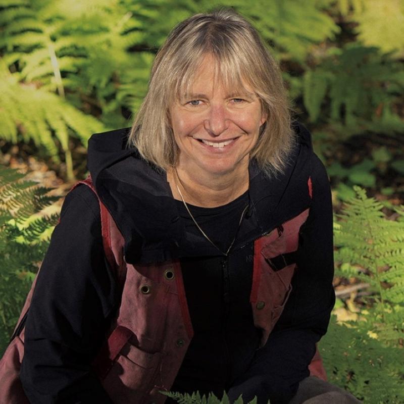 Suzanne Simard smiling in front of a natural background.