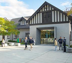 Students walk past the entrance of a building at Royal Roads University