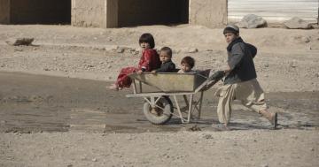 Photo of young children in Afghanistan in difficult conditions; children are sitting in a wheelbarrow