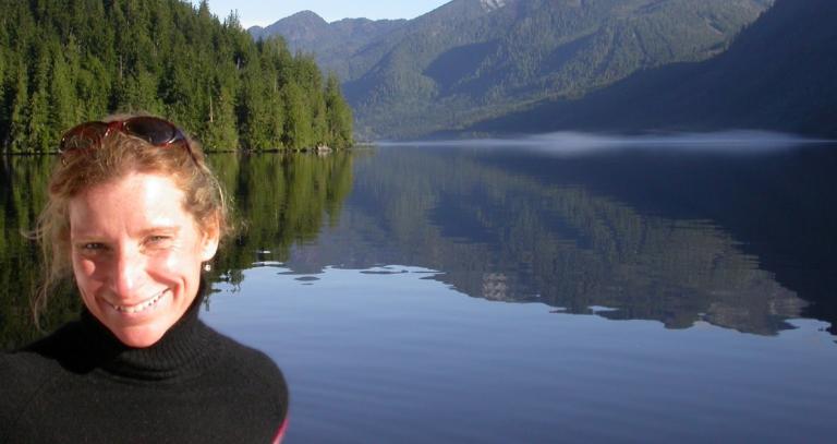 RRU marine geologist standing in front of a forest/mountain backdrop