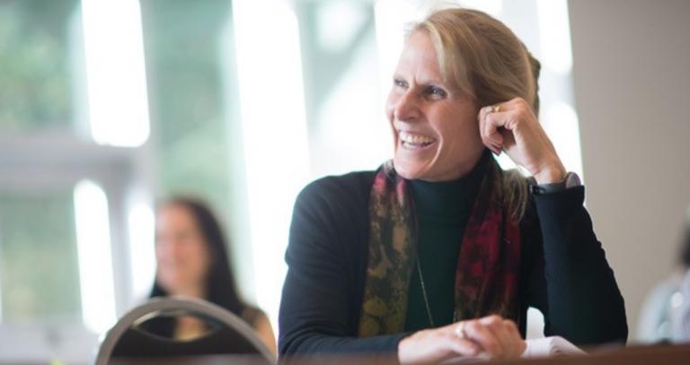 Dr. Jennifer Walinga smiling at a desk in class