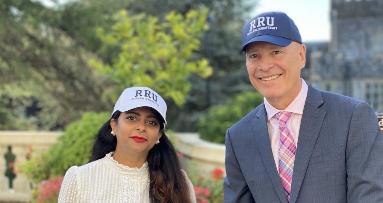 Student Prapti Yadav and President Philip Steenkamp outside Hatley Castle wearing RRU ballcaps.