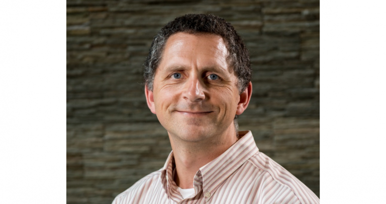 Head shot of Eugene Thomlinson with a stone wall behind him