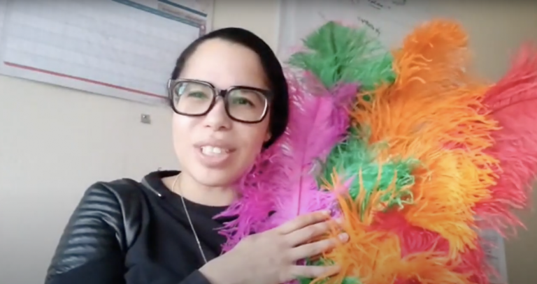 Odion Welch, a first generation Caribbean-Canadian, holding a colourful headpiece.