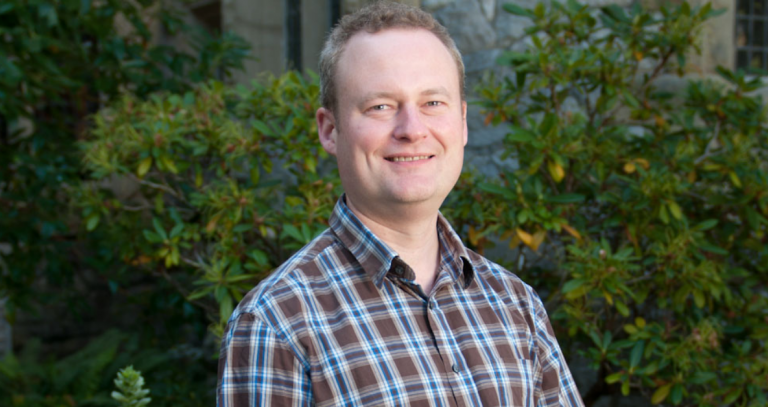 Head shot of Chris Ling with a bush in the background