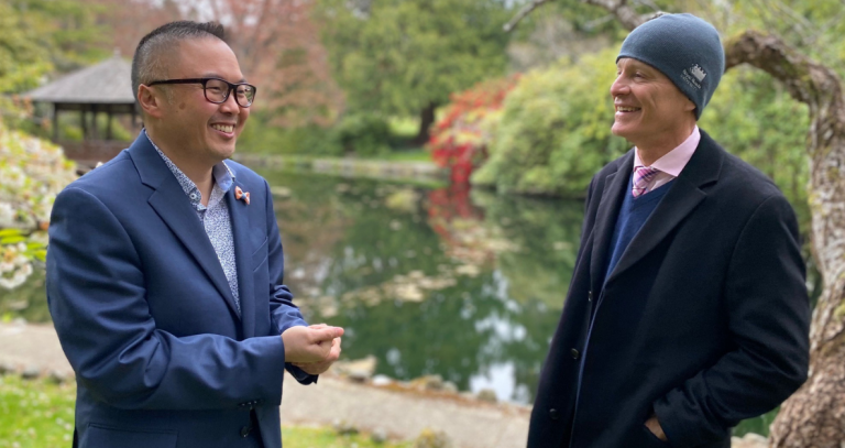 Nelson Chan and Philip Steenkamp smile while in conversation in Royal Roads' Japanese Garden.