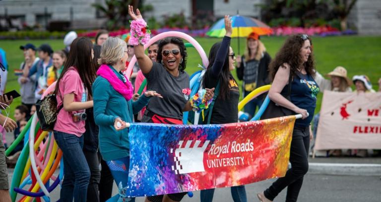 RRU Proud walk in the Pride parade behind an RRU banner.