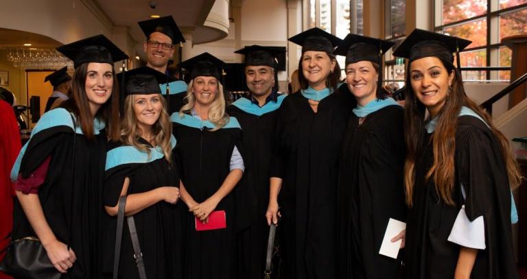 Smiling people wearing Convocation regalia at the 2019 Convocation held at the Royal Theatre in Victoria.