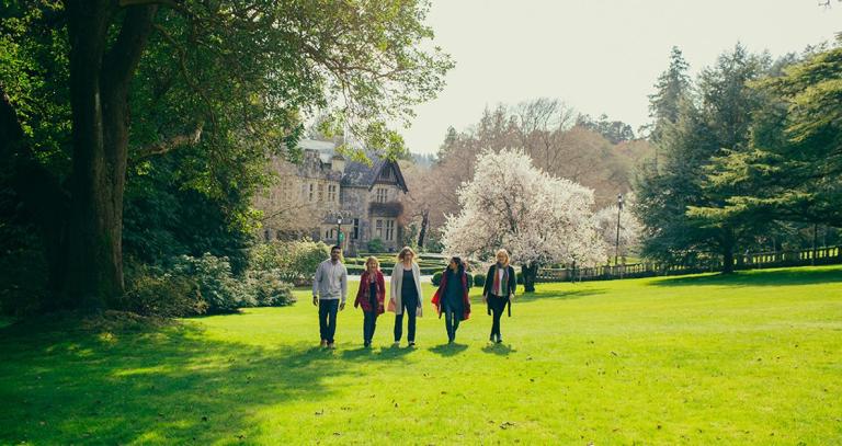 A line of RRU staff walk side-by-side on the greens of campus