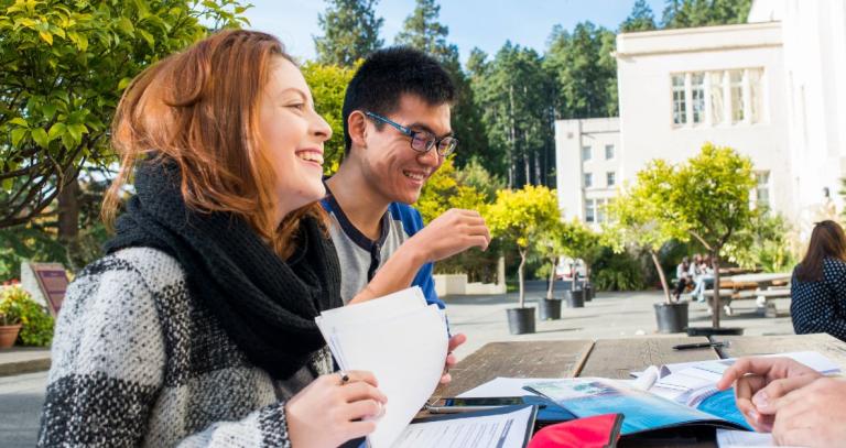 International students sit around a picnic table at Royal Roads University. 