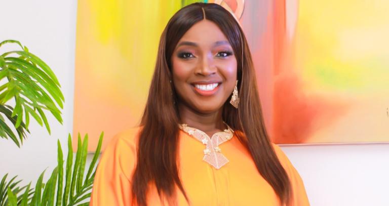 Anuli Ausbeth-Ajagu smiles in front of an orange and yellow painting