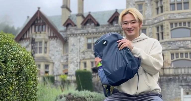 Bojie sits outside Hatley Castle, holding a backpack.