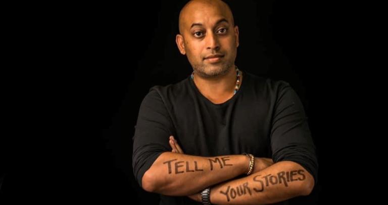 Sharad Khare in front of black background. His arms have Tell Me Your Stories written on them.