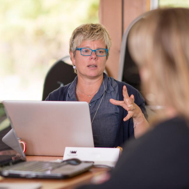 Person-sitting-in-front-of-laptop-gesturing-with-hand