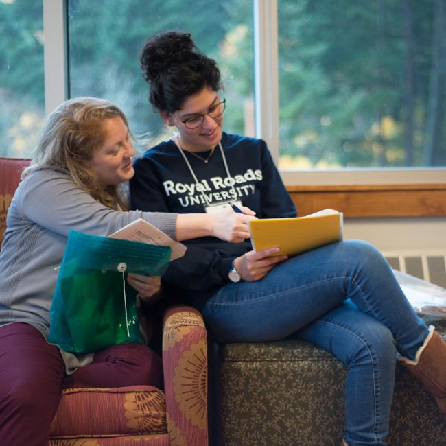 Two-students-sitting-looking-at-documents-together