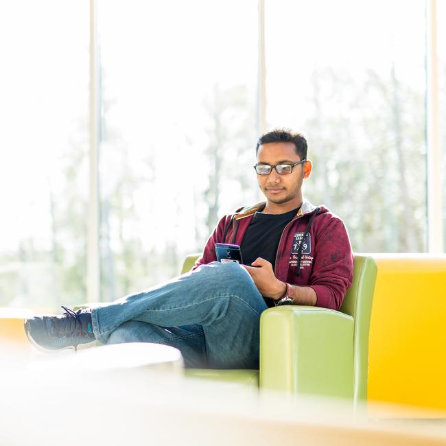 Student sitting in bright green chair, with yellow 