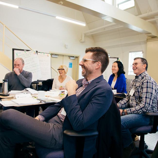 Group-sitting-around-board-table-laughing-and-engaged