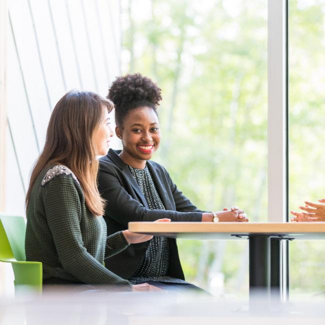 Two women at a table, one smiling broadly