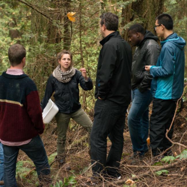 Students in the forest engaged in a class discussion.