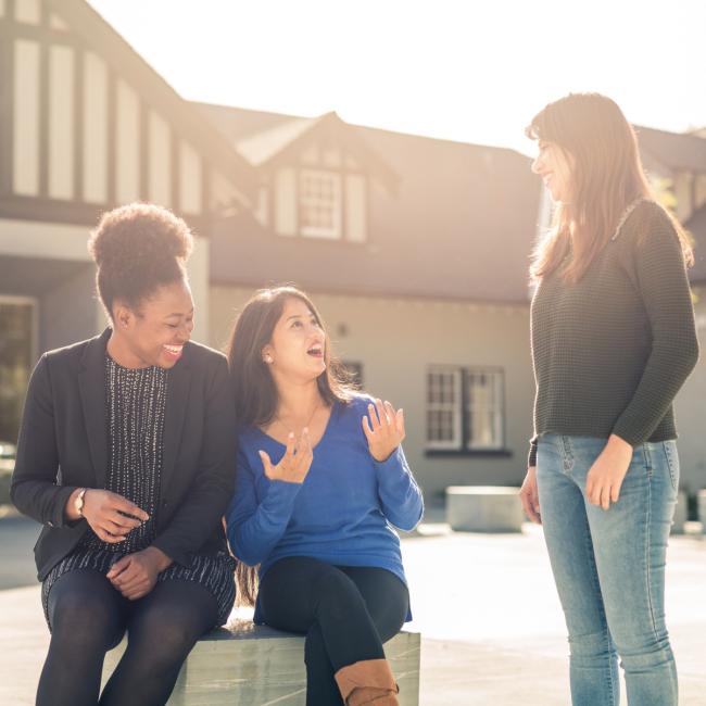 Three Royal Roads University students in conversation outdoors.