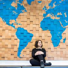 Student sits in front of a wooden map of the world.